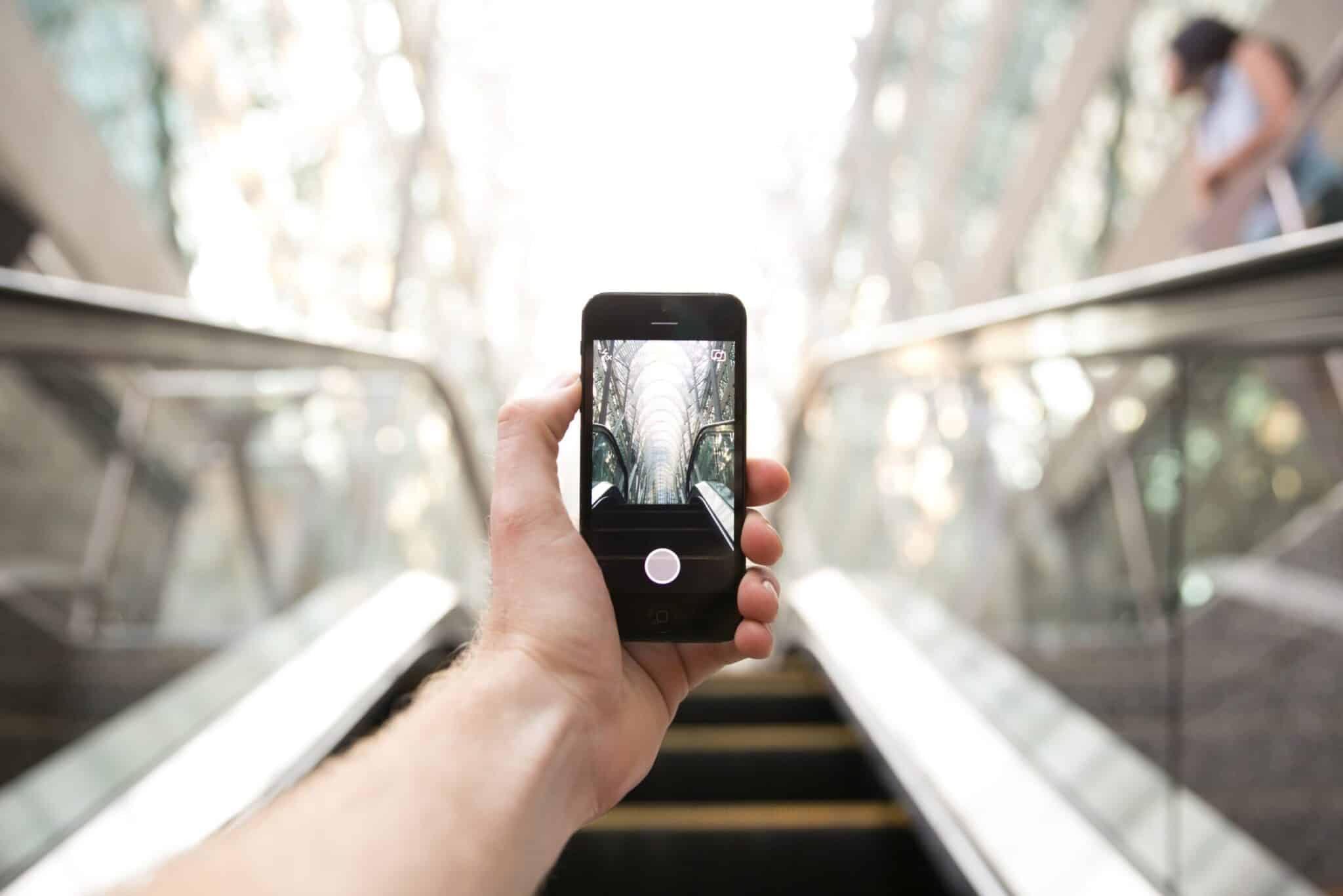 Une main tient un téléphone portable et prend une photo en extérieur